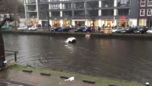 Cativa pietoni se arunca in apa rece a unui canal din Amsterdam si salveaza o femeie blocata in masina