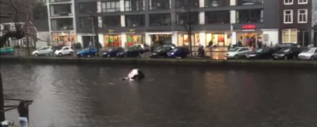 Cativa pietoni se arunca in apa rece a unui canal din Amsterdam si salveaza o femeie blocata in masina