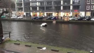 Cativa pietoni se arunca in apa rece a unui canal din Amsterdam si salveaza o femeie blocata in masina