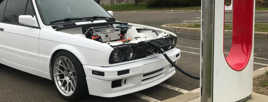 Nu i-a venit sa creada ce vede in parcare. Un BMW E30 Cabrio se incarca linistit la o priza TESLA Nu i-a venit sa creada ce vede in parcare. Un BMW E30 Cabrio se incarca linistit la o priza TESLA