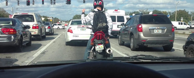 Un motociclist danseaza cu foc in timp ce asteapta la semafor
